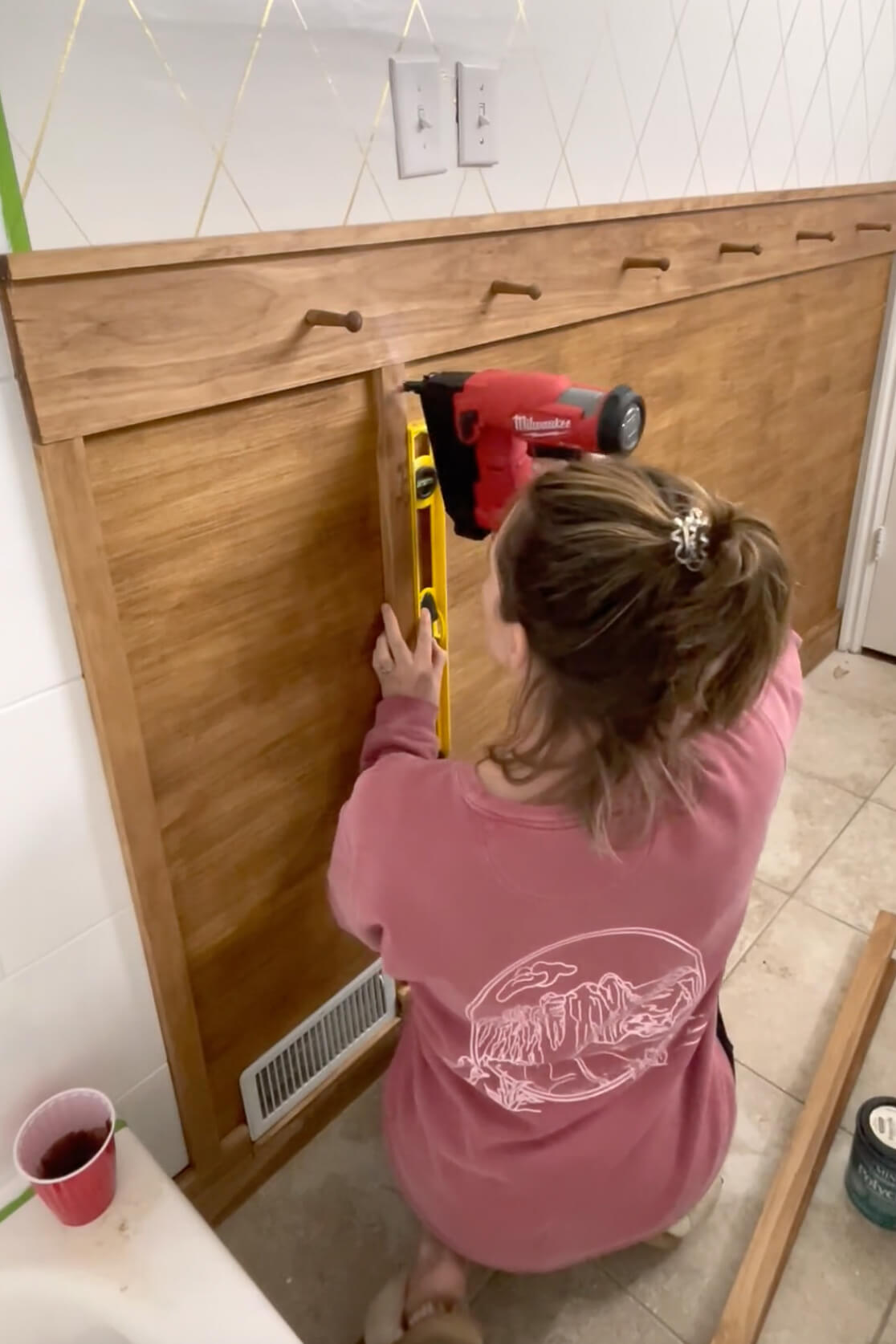 Attaching battens to a board and batten bathroom wall using a brad nailer.